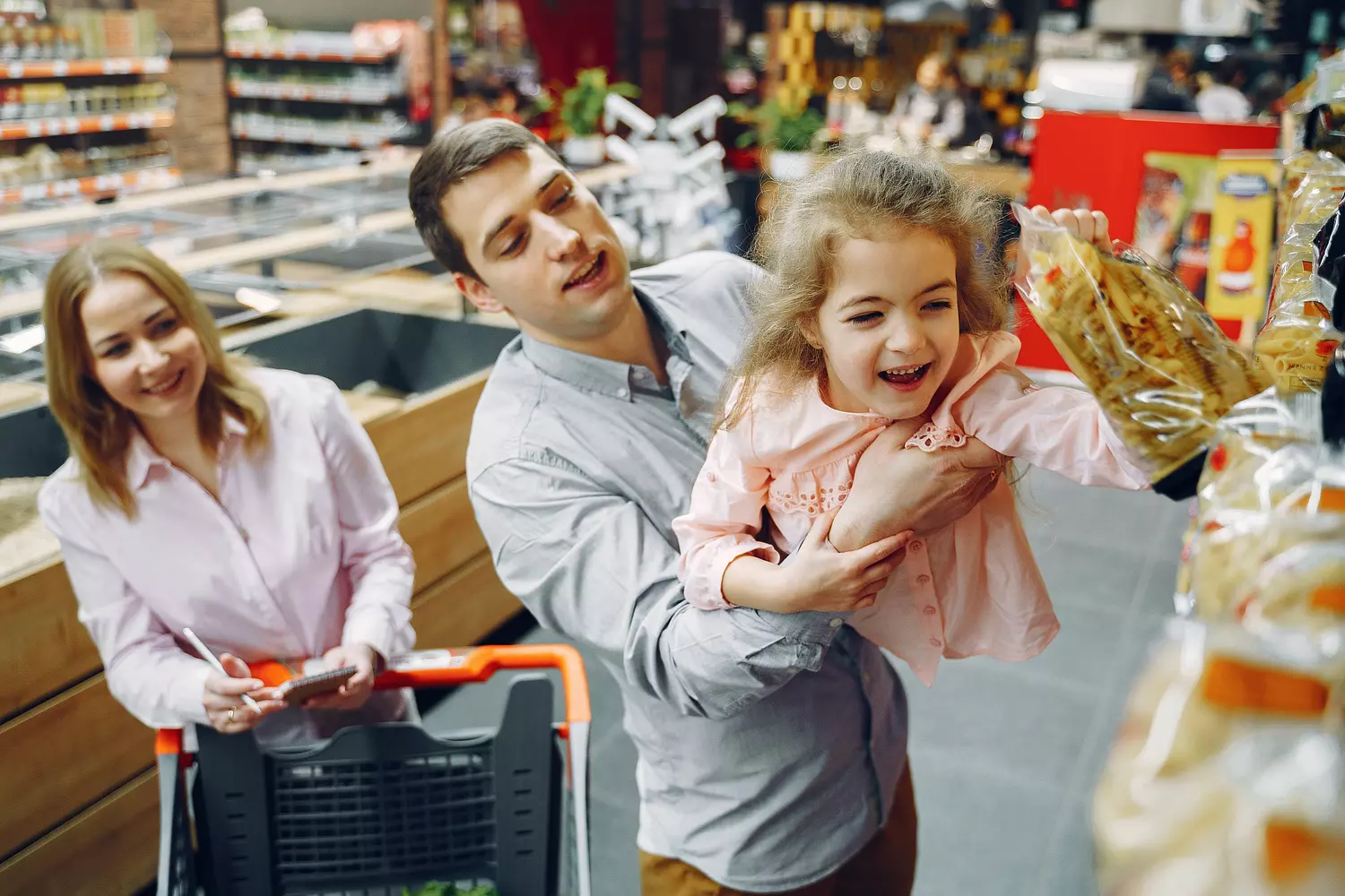 besparen boodschappen - vader tilt kind in supermarkt die pasta pakt
