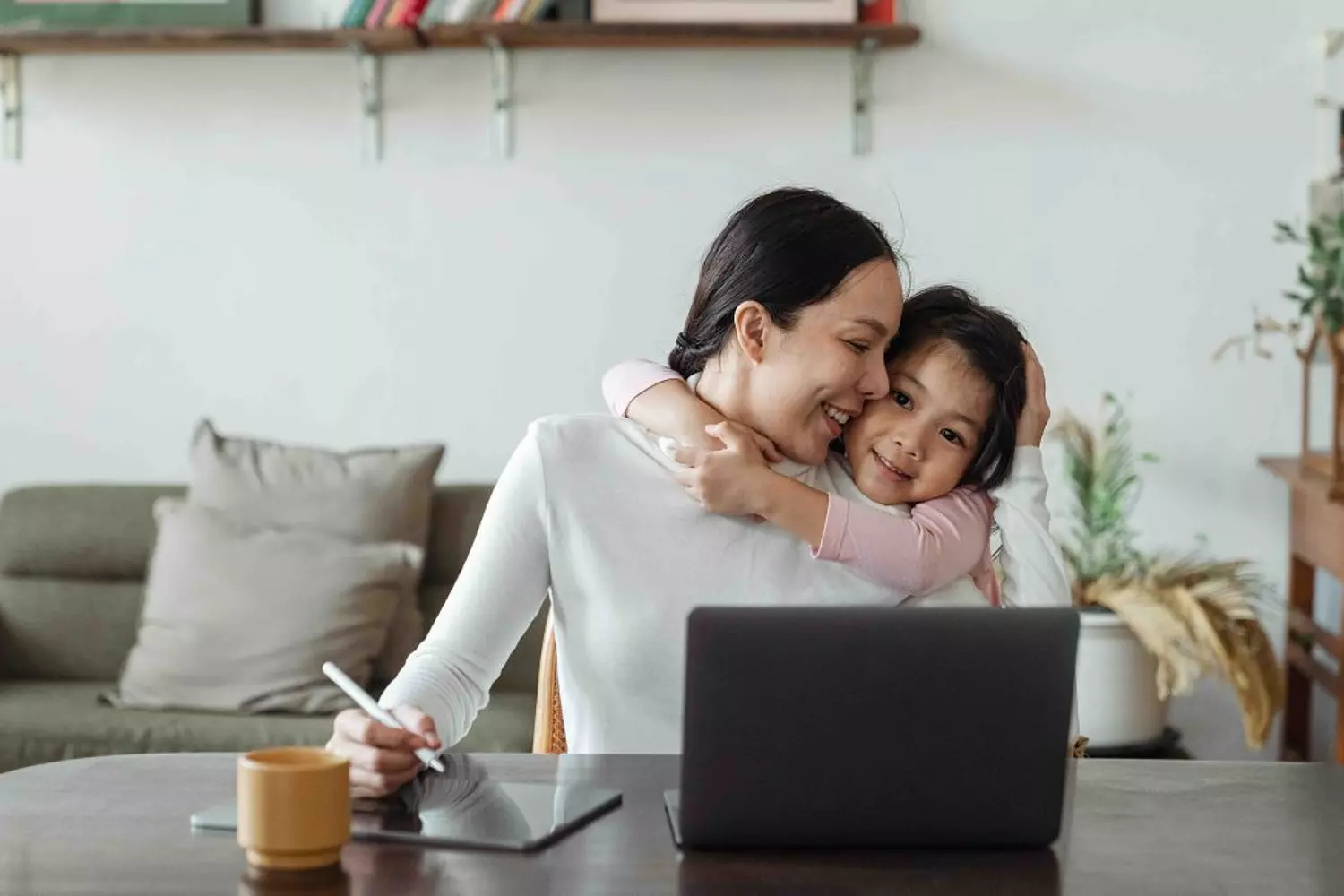 sparen voor je kind - moeder op laptop en kind hangt aan nek