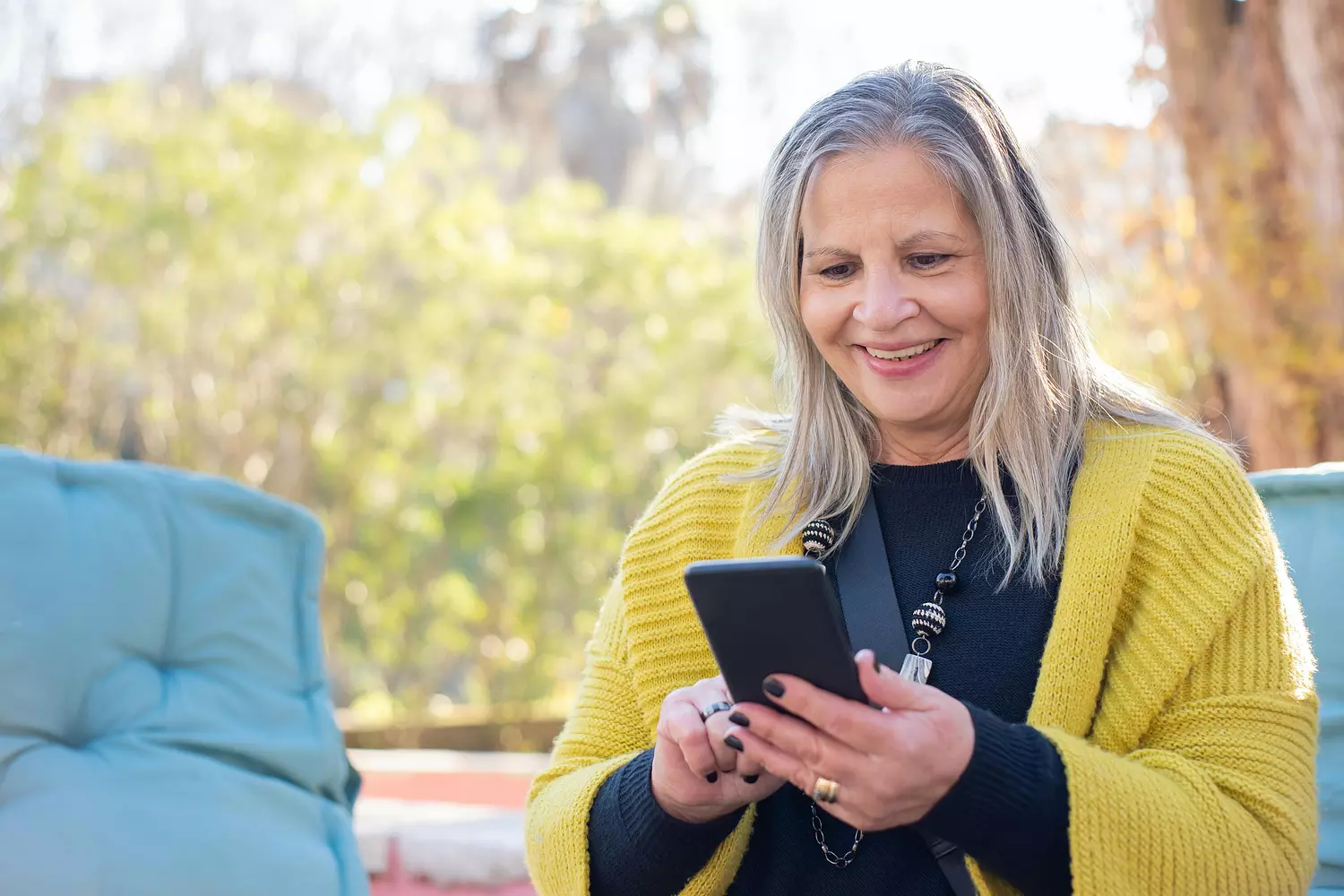 loonheffingskorting - lachende vrouw met grijs haar kijkt op haar telefoon